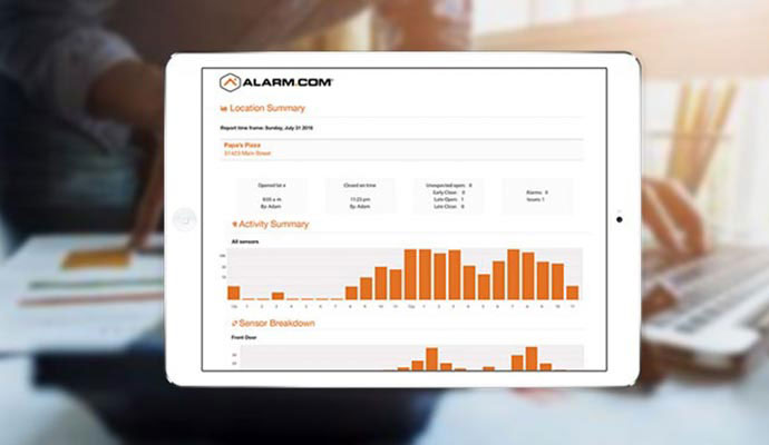 A tablet displays an Alarm.com security report.