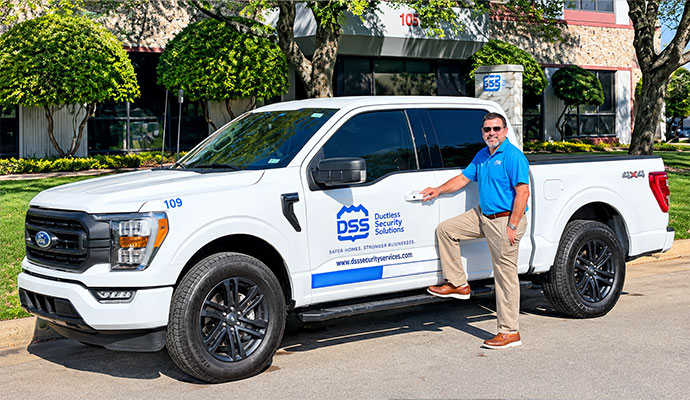 Person standing with a Dallas Security Systems service vehicle