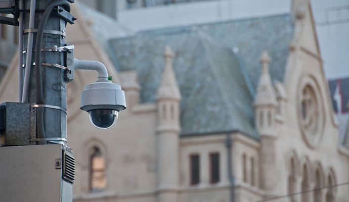 White dome camera on pole near stone church