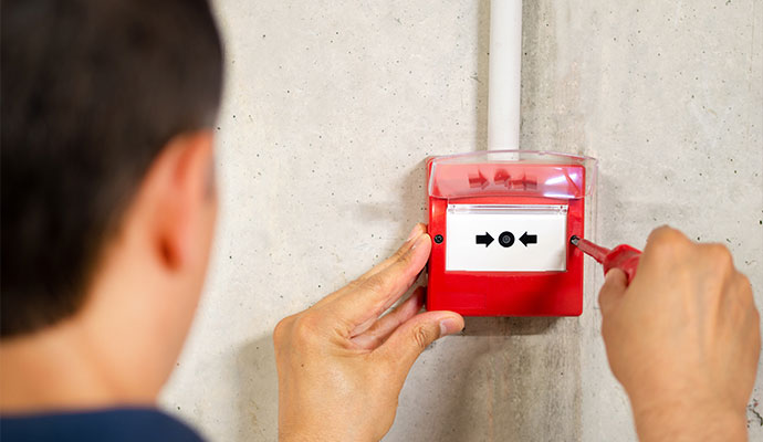 Technician installing commercial fire alarm pull station