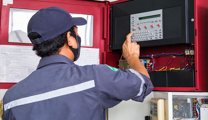 Technician operating commercial fire alarm control panel