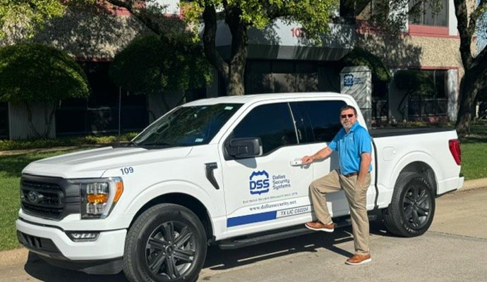 Dallas Security Systems technician standing beside branded service truck