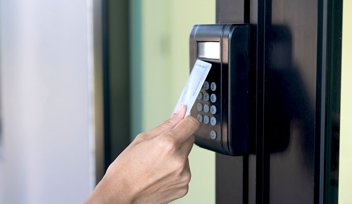A person scanning a keycard on an electronic door access control reader keypad