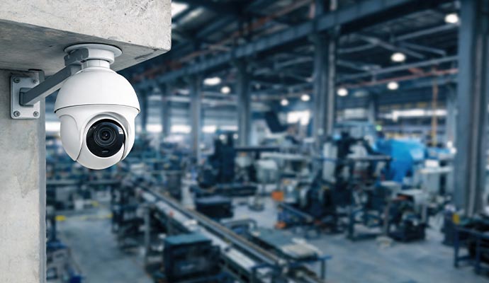 White dome security camera overlooking an industrial warehouse floor
