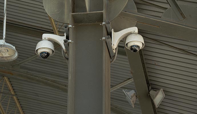 Two white indoor dome security cameras mounted on a metal beam