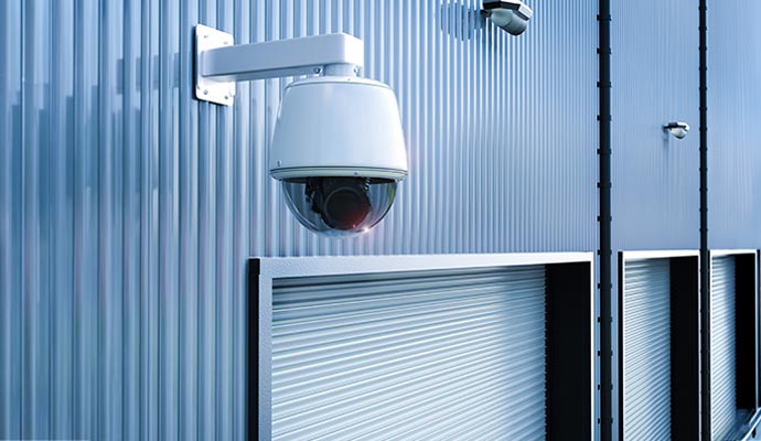 White outdoor dome security camera on blue corrugated metal wall