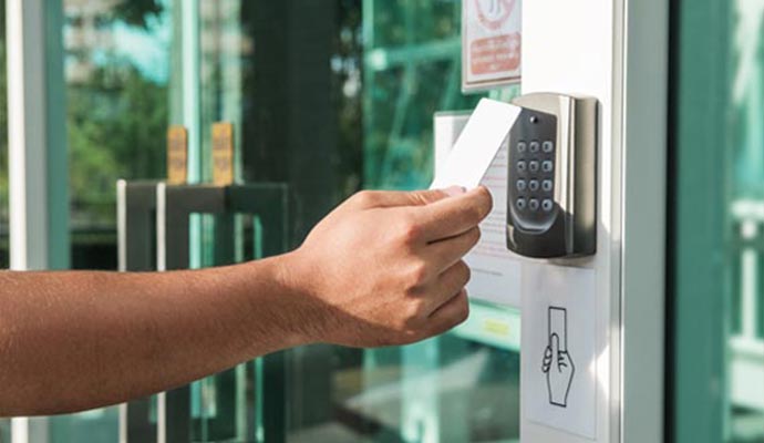 Person holding a key card near a touchless door access control reader for entry
