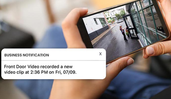Person viewing security camera footage on a smartphone with a notification about a recorded video clip