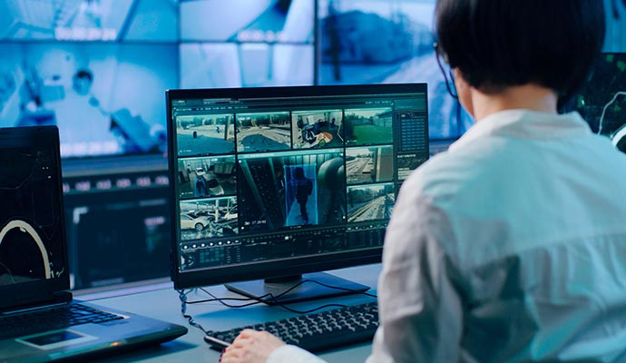 Security professional monitoring multiple camera feeds in a control room