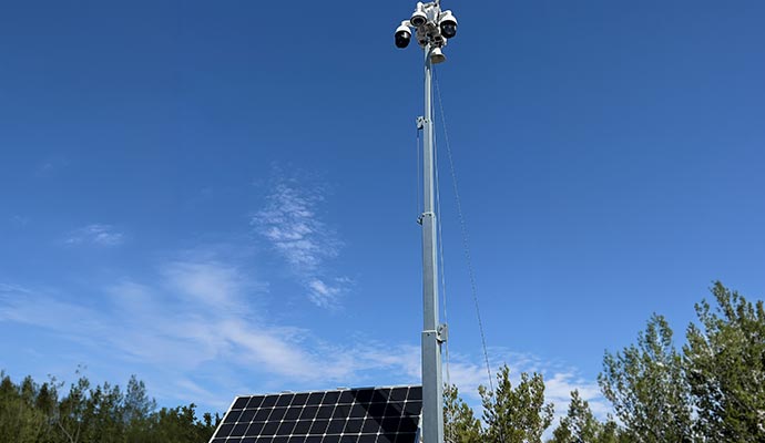 Solar-powered mobile surveillance trailer with a high-reach camera.